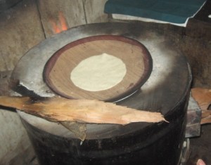 Cooking the tortilla on pottery over a wood stove